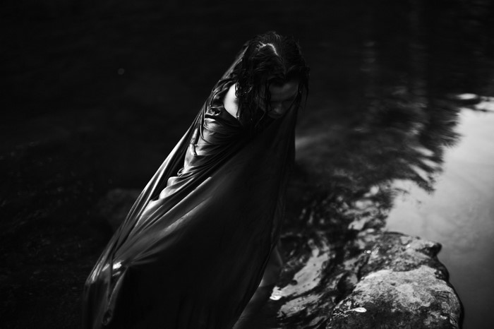 Monochrome photo of a woman in a dark, wet environment