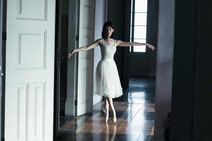 Ballerina in a white tutu dancing in a room