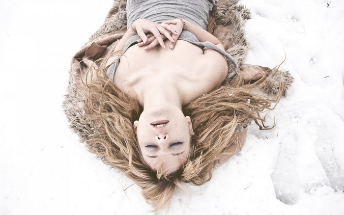 Woman lying in snow with fur blanket