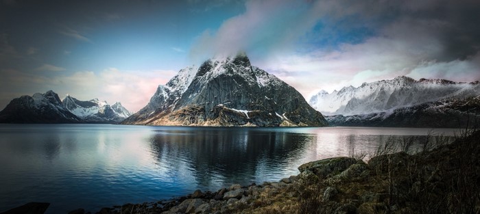Snowy mountains reflected in a calm fjord in Norway