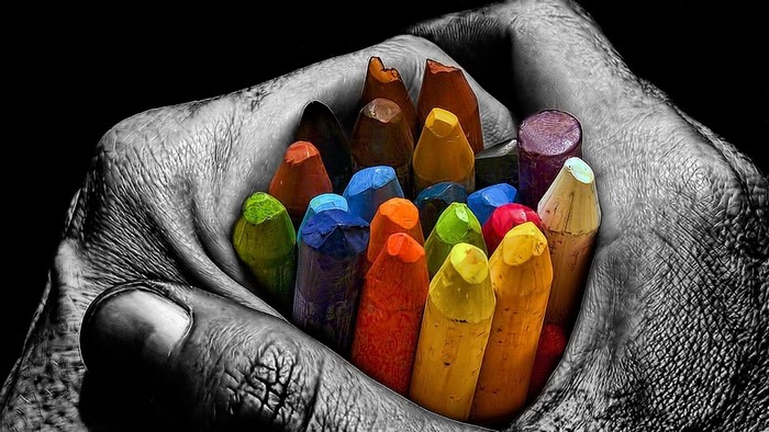 Hand holding colorful crayons with selective coloring