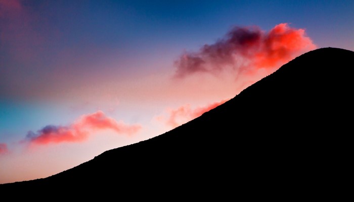 Silhouette of a mountain against a colorful sunset sky