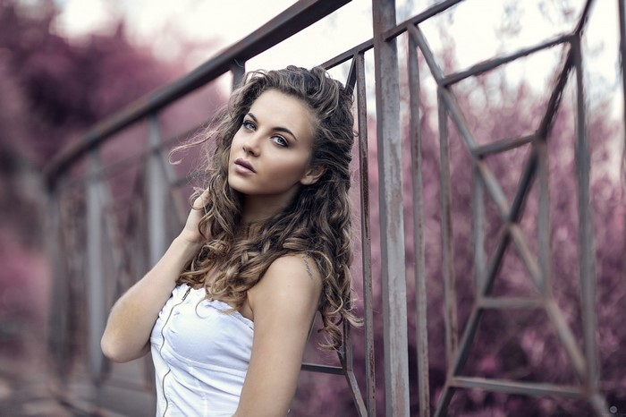 Portrait of Woman with Curly Brown Hair by Metal Fence