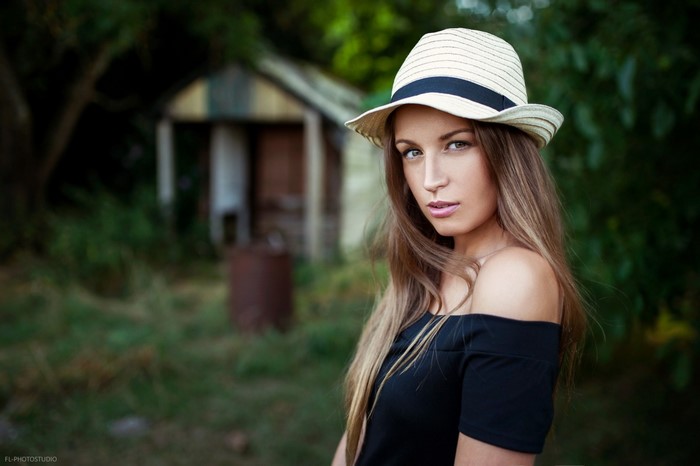 Woman wearing a hat and black off-the-shoulder top