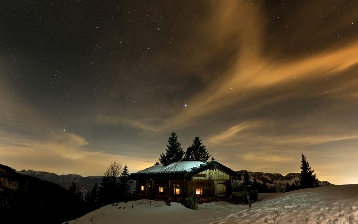 Wooden cabin under starry night sky with clouds