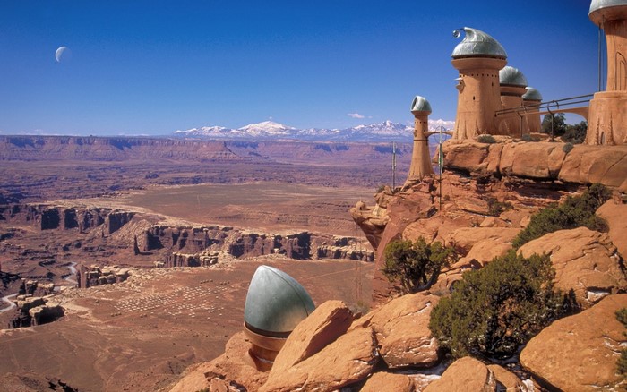 Alien structures on a canyon cliff overlooking a desert valley