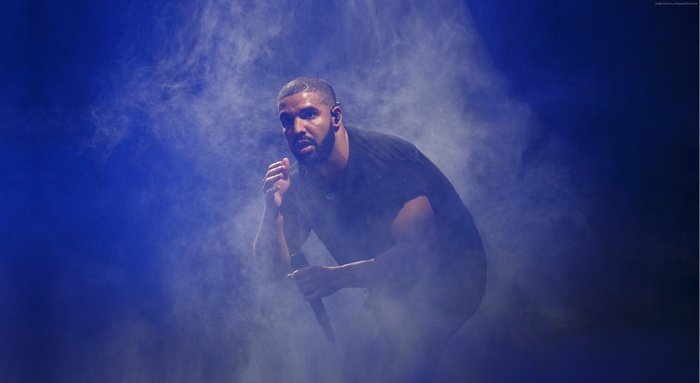 Drake performing on stage with blue smoke