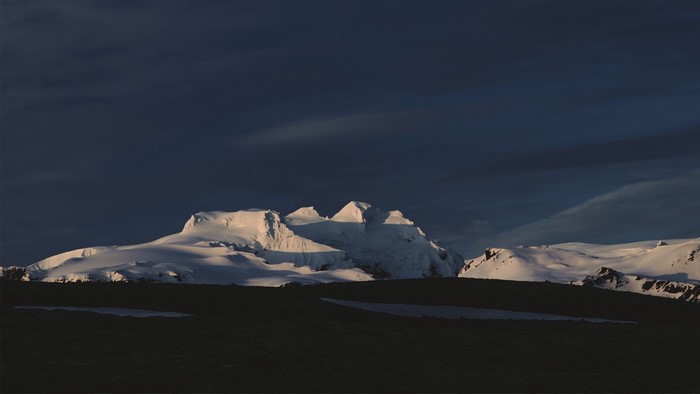 Snow-covered mountains under a dark sky