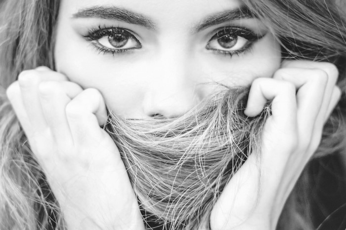 Monochrome portrait of a woman with hair covering her mouth