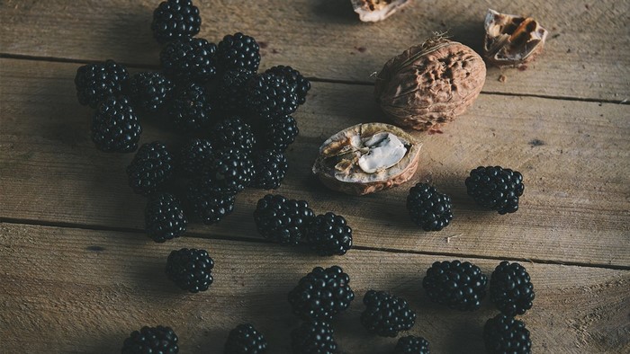 Blackberries and walnuts on a wooden surface