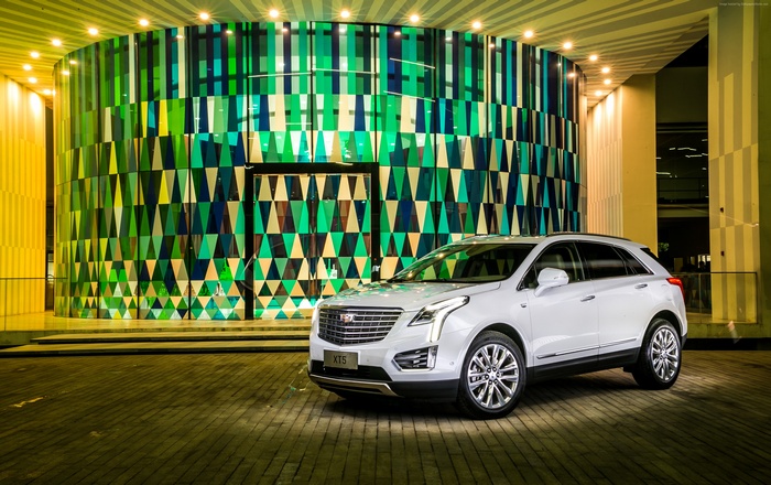 White Cadillac XT5 parked in front of a modern building