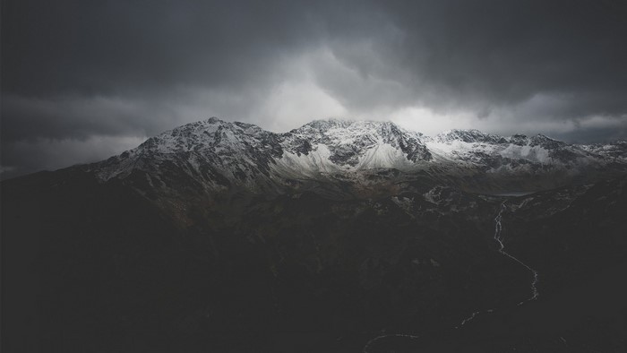 Snow-capped mountains under dark clouds