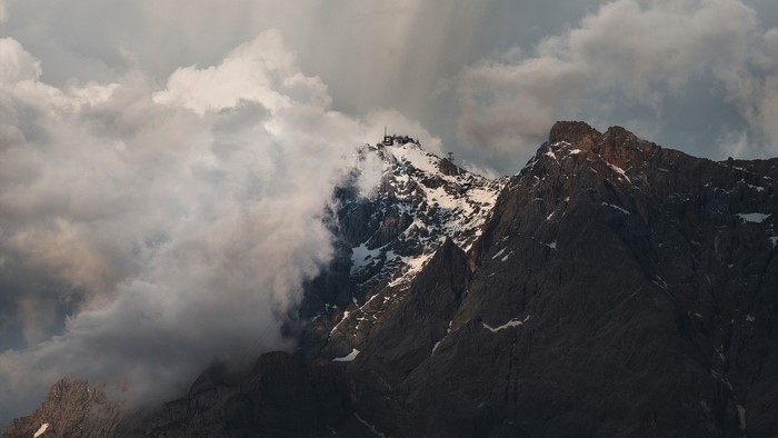 Snow-capped mountain summit with clouds and sunlight