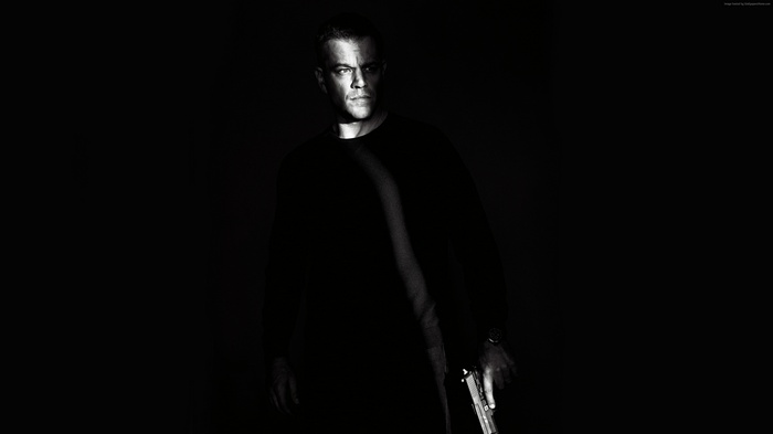 Matt Damon as Jason Bourne holding a gun