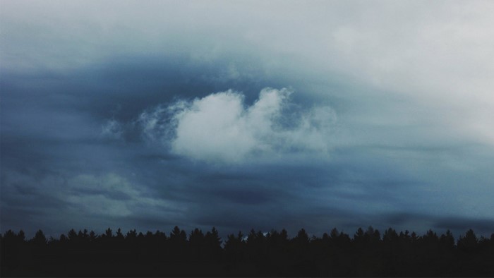 Dark storm clouds over a silhouetted forest