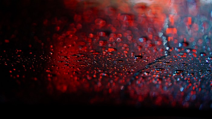 Water drops on a dark surface with red bokeh lights
