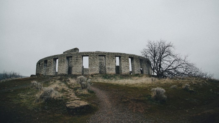 Stonehenge replica on a hill with a bare tree