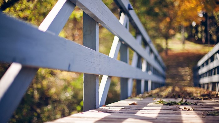 Wooden bridge railing in autumn sunlight