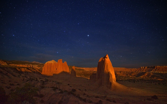 Desert landscape with rock formations under a starry night sky