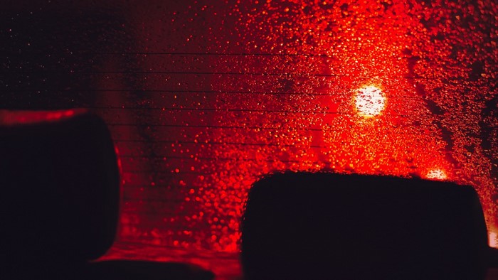 Red lights on a rainy car window at night