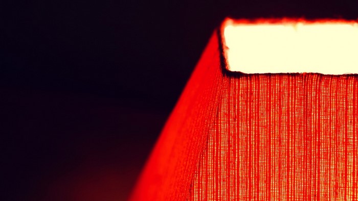 Close-up of a red lampshade with light shining through