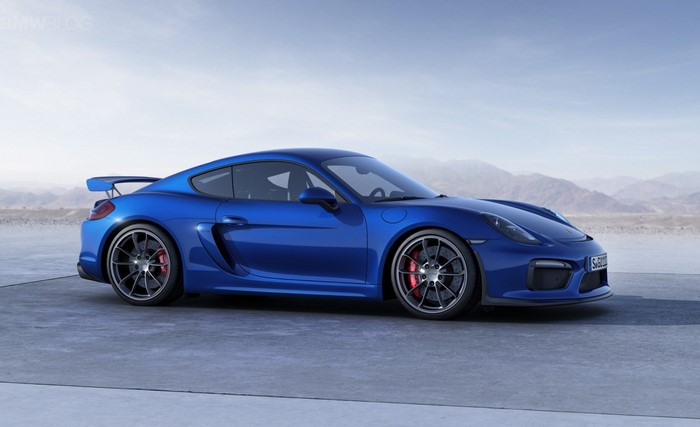 Blue Porsche Cayman GT4 parked on concrete with mountains in background