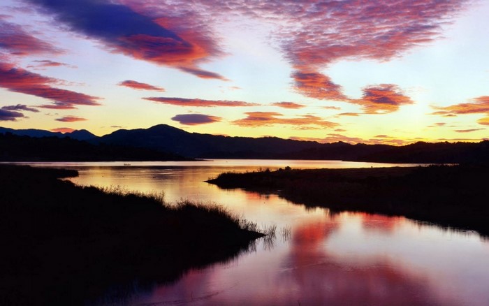Sunset over a lake with colorful clouds and mountains