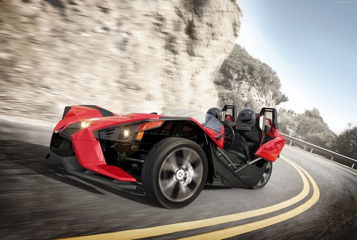 Red Polaris Slingshot driving on a winding road