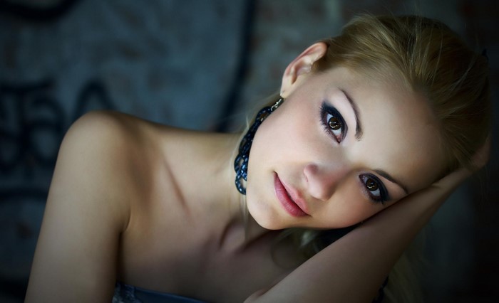 Woman with blonde hair and blue earrings posing