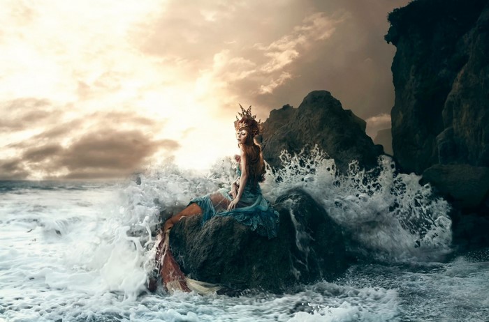 Mermaid sitting on a rock in the ocean waves