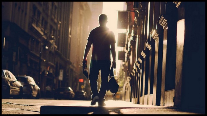 Man walking down a city street at sunset