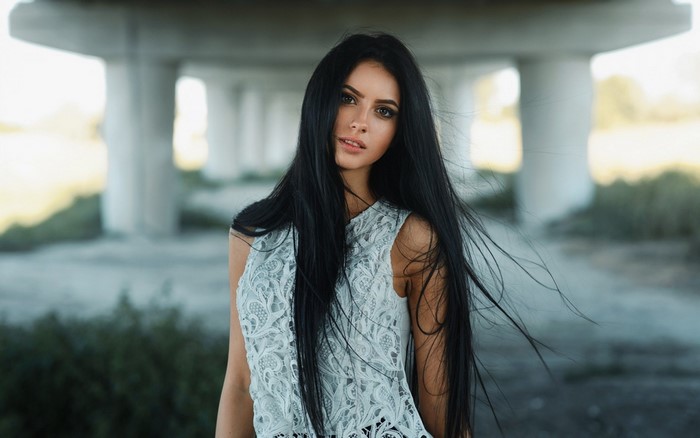 Woman with long black hair under a bridge