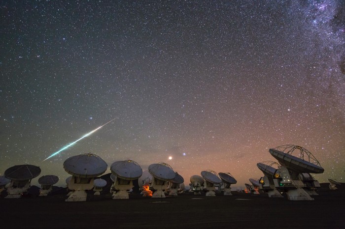 Meteor streaks across starry sky above ALMA Observatory dishes