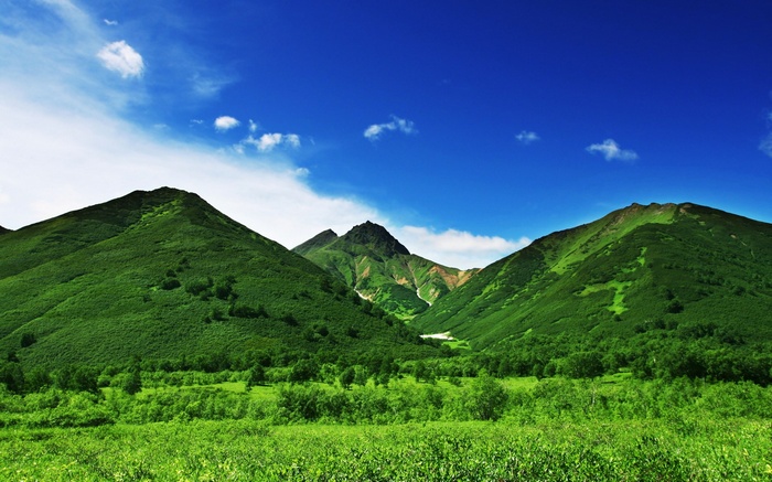 Green mountains under a blue sky with clouds