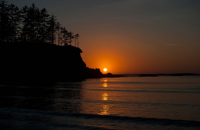 Sunset over the ocean with a cliff and trees