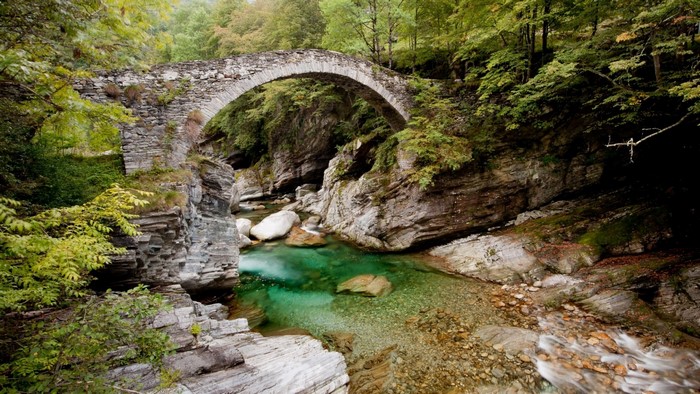 Stone bridge over a clear river in a forest