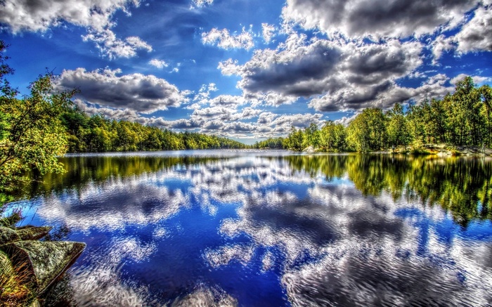 Lake reflecting trees and clouds under a blue sky