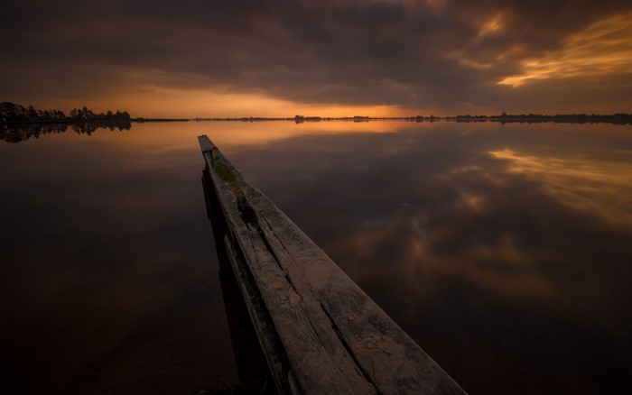 Sunset over a calm lake with a wooden pier