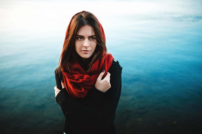 Woman wearing a red scarf and black sweater by the water
