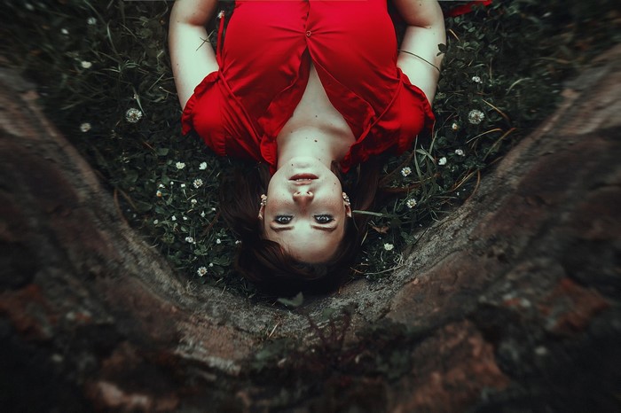 Woman in red dress lying in grass with flowers
