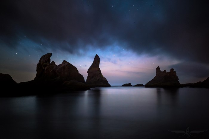 Rocky sea stacks under starry night sky