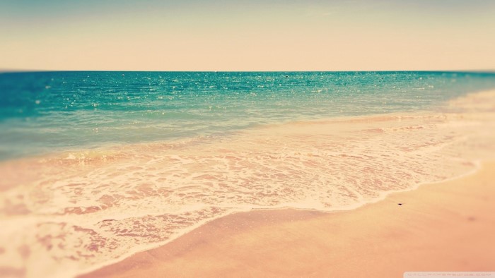 Ocean waves on a sandy beach at sunset