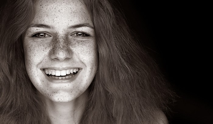 Monochrome portrait of a smiling woman with freckles