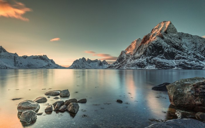 Snowy mountains reflected in a calm lake at sunset