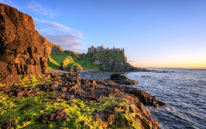 Dunluce Castle on a rocky coast at sunset