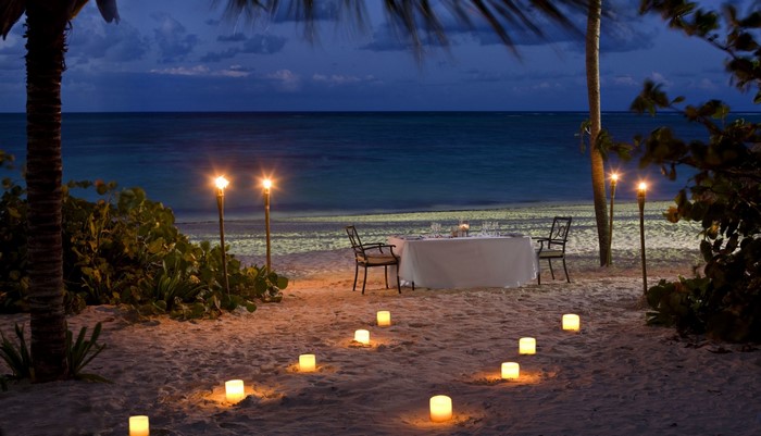 Romantic beach dinner at night with tiki torches and candles
