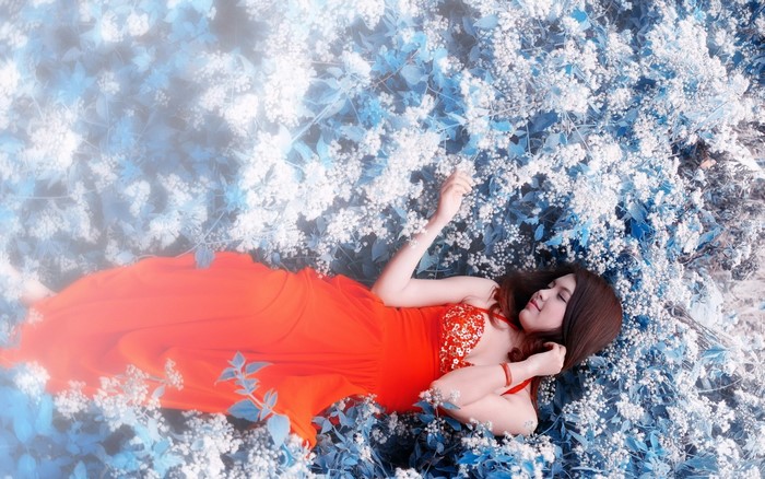 Woman in red dress lying in blue flowers