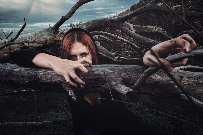 Woman with red hair emerging from fallen trees