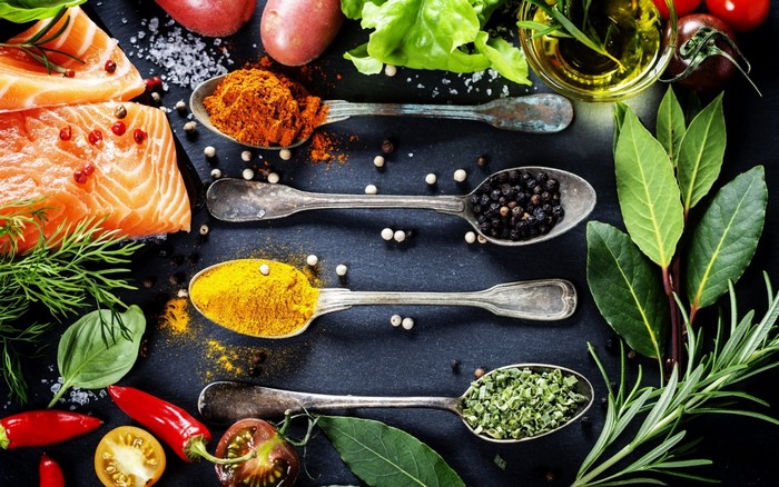 Salmon, spices, and fresh ingredients on a dark surface