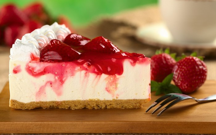 Slice of strawberry cheesecake with whipped cream and strawberry topping